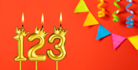 Number 123 candle - Birthday celebration on an orange background with pennants