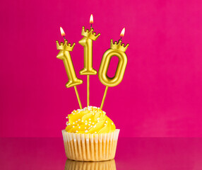 Yellow birthday cupcake with a number 110 candle - Birthday card on a pink background