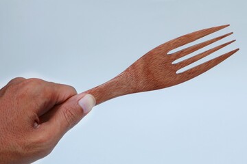 Hand holding wooden fork on white background