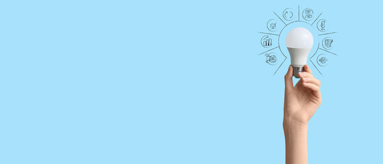 Female hand with white light bulb on blue background