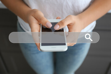 Young woman using modern mobile phone at home, closeup
