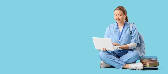 Female medical student with laptop on blue background with space for text