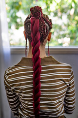Rear view detail of a meticulously crafted braided hair bun with striking color accents