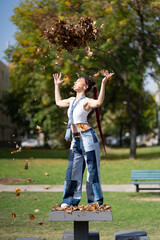 Young woman playing with falling leaves in a park