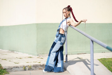 Young woman with braids and patchwork denim leaning on railing
