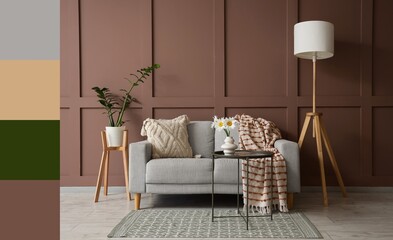 Interior of living room with grey sofa, floor lamp and chamomiles in vase. Different color patterns