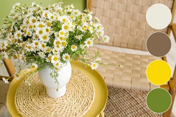 Vase with chamomiles on table in living room. Different color patterns