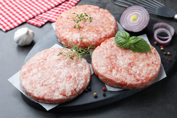 Fresh raw patties for burger and spices on grey table, closeup