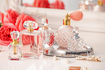 Bottles of different perfumes, accessories and flowers on dressing table indoors, closeup