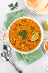 Traditional Indian dal soup with red lentils, spices, fresh cilantro and lime on a white background. Indian food