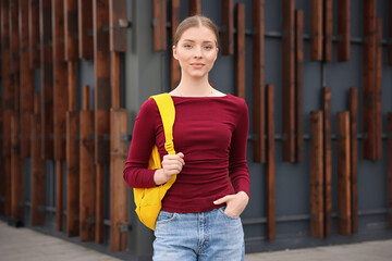 Teenage girl with backpack near building outdoors