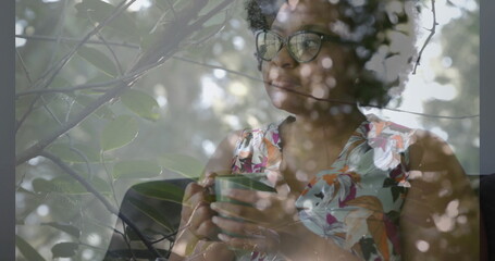 Holding green mug woman wearing floral blouse and glasses gazing at window, copy space