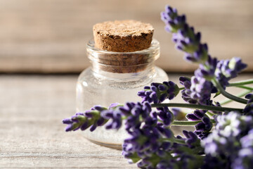 Natural essential oil and lavender flowers on wooden table, closeup