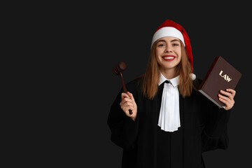 Young female judge in Santa hat on black background