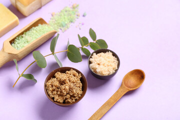 Scrubs with sea salt, wooden spoon and eucalyptus on lilac background. Body massage concept