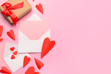 Envelopes with blank card, gift box and red paper hearts on pink background. Valentine's Day...