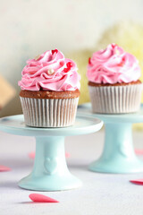 Stand with tasty cupcakes for Valentine's Day on light background