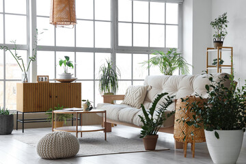 Interior of light stylish living room with comfortable sofa, wooden chest drawer, table,...