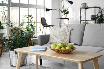 Interior of modern living room with comfortable sofa, lamp, houseplants, shelving units and table...
