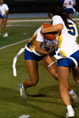 Youth flag football game with blue and white teams playing on grassy field, kids competing in sports under sunny sky, athletic teamwork, childhood activity, outdoor fun, amateur league.