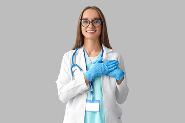 Young female doctor on light background
