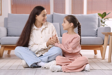 Apologetic mother with her daughter holding hands at home