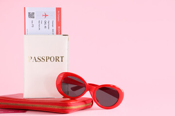 Passport with ticket, wallet and sunglasses on pink background