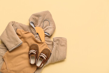 Hanger with baby bodysuit, jacket and booties on color background