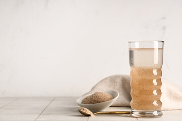 Glass of water with psyllium husk on light background