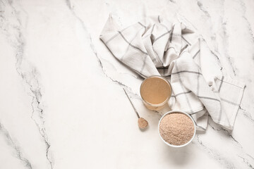 Glass of water with psyllium husk on light background with space for text