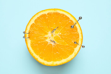 Half of orange fruit with piercing on blue background