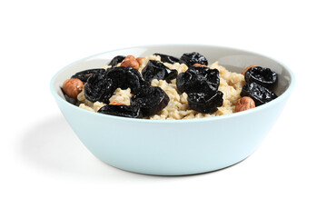 Bowl of tasty oatmeal with prunes and hazelnuts on white background