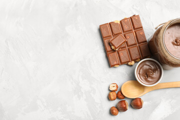 Bowl and jar of sweet chocolate spread with hazelnuts on grey background