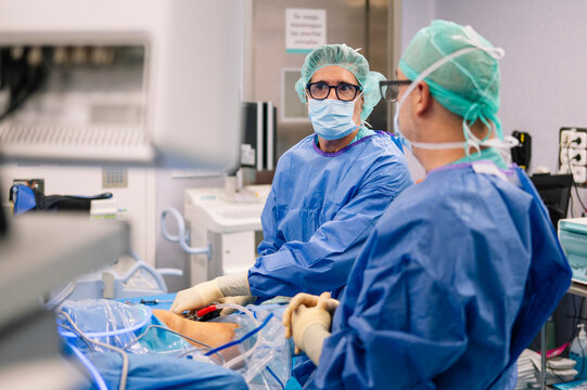 Two doctors discuss surgical progress while examining screen and maintaining sterile field
