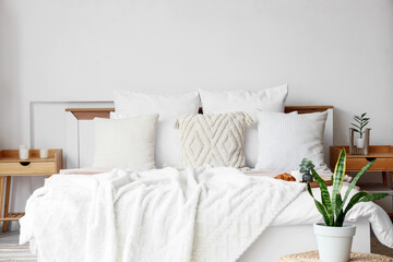 Big comfortable bed and bedside tables in interior of modern bedroom