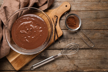 Bowl with hot chocolate, whisk and cocoa in sieve on wooden background. Top view