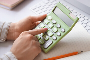 Female accountant with calculator and notebook at table in office