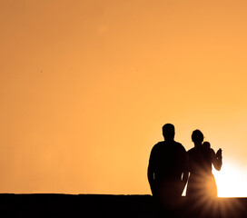 people in the park. happy family walking silhouette at sunset. mom dad and kid son walk holding on hands. happy family childhood concept. parents and children sun go back on sunset sky background