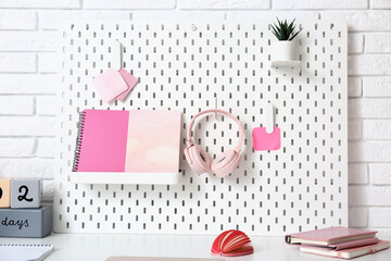 Pegboard with stationery and headphones on table in office