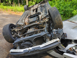 Vehicle is overturned on muddy path surrounded by greenery after likely recent accident