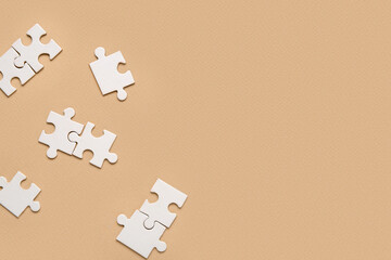 White puzzle pieces on beige background. Logic concept