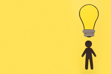 Silhouette of human with paper light bulb on yellow background. Logic concept
