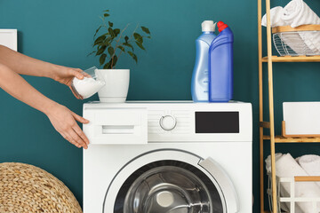 Young woman pouring powder in washing machine at home, closeup