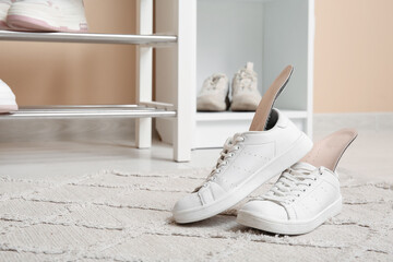 Sneakers with orthopedic insoles on carpet in hallway, closeup