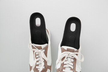 Sneakers with orthopedic insoles on light background, closeup