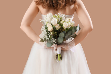 Beautiful bride in white wedding dress with flowers on beige background, back view