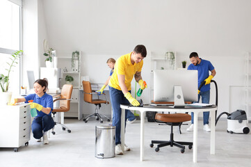 Team of young janitors cleaning in office