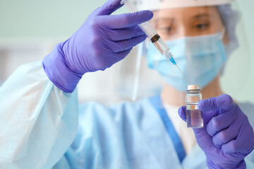 Female scientist with ampule and syringe in laboratory, closeup
