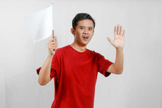 Asian man holding a white flag while raising his hands in surrender