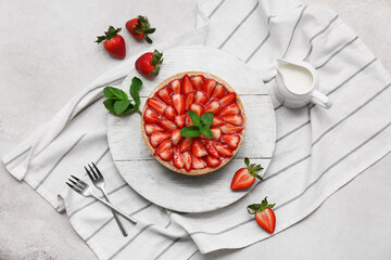 Wooden board of sweet strawberry tart with mint and jug of fresh milk on white background